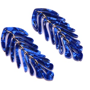 Könnte beinhalten: Ein Paar blaue Statement-Ohrringe mit einem Blattdesign. Die Ohrringe sind aus einem strukturierten Material gefertigt und haben ein goldenes Kettendetail.