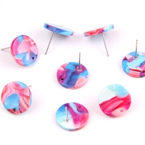 Puede incluir: Seis pares de pendientes redondos y coloridos con un patrón de mármol en tonos rosa, azul y blanco. Los pendientes tienen postes plateados.