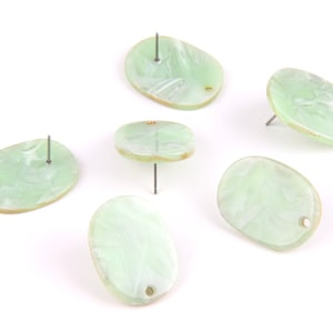 May include: Six green oval-shaped earrings with a swirl pattern. Each earring has a small hole at the top and a silver post.