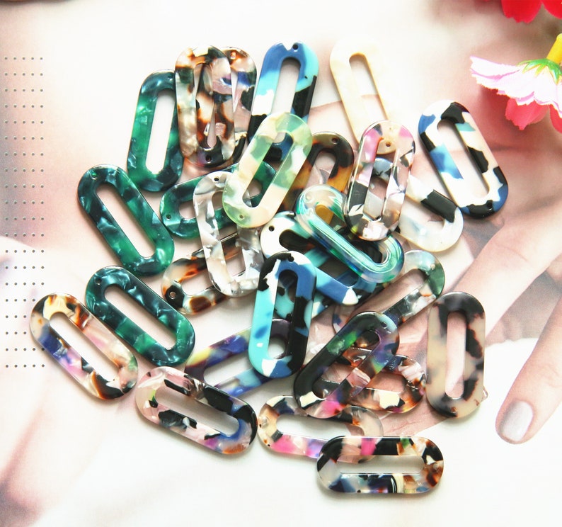 May include: Assortment of colorful oval-shaped plastic charms with a hole in the center. The charms have a mottled, marbled pattern in shades of blue, green, pink, and white.