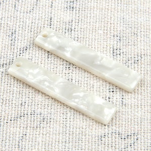 May include: Two white rectangular resin hair clips with a marbled pattern.