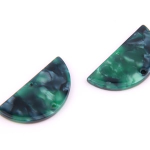 Puede incluir: Dos colgantes de resina de forma semicircular de color verde y negro con agujeros para encordar.