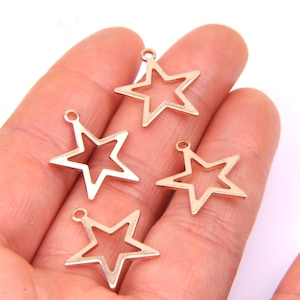 May include: Four gold-toned metal star-shaped charms with a loop at the top for attaching to jewelry or other crafts.