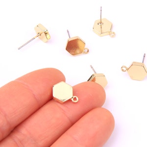 May include: Five gold-toned hexagonal earring blanks with jump rings. The blanks are flat and have a smooth finish. The earring posts are silver-toned.