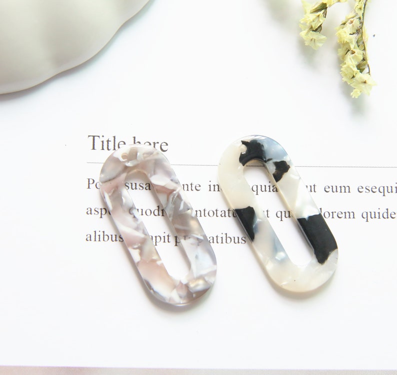 May include: Two oval-shaped hair clips with a marbled pattern in shades of white, black, and gray. The clips have a smooth, glossy finish.