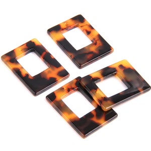 Puede incluir: Cuatro marcos rectangulares de plástico marrón y negro con estampado de caparazón de tortuga con una abertura cuadrada en el centro.