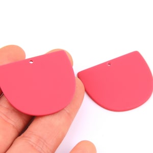 Op de afbeelding: Twee roze halve cirkelvormige acryl blanks met een gat in het midden. Deze blanks zijn perfect voor het maken van oorbellen of andere sieraden.