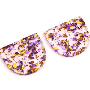 May include: Two clear, half-circle shaped resin earrings with gold and purple glitter embedded inside.