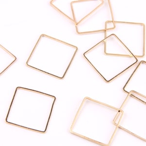 Puede incluir: Una colección de diez anillos de salto cuadrados de metal dorado. Los anillos de salto son todos del mismo tamaño y forma, y están dispuestos en un patrón aleatorio sobre un fondo blanco.