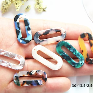 May include: Assortment of oval-shaped plastic embellishments with different patterns and colors, including blue, white, green, brown, and black. The embellishments have a hole at the top for attaching to a project. The dimensions are 30*13.5*2.5mm.