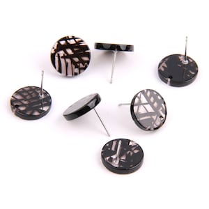Puede incluir: Seis pares de pendientes de botón con estampado en blanco y negro. Los pendientes son redondos y tienen una espiga plateada.