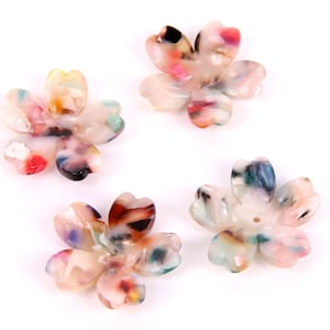 May include: Four colorful plastic flower-shaped beads with a hole in the center. The beads are white with swirls of pink, blue, green, and brown.
