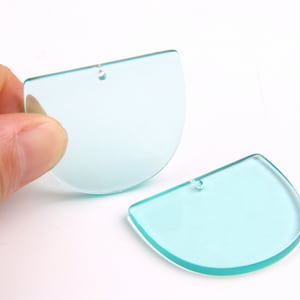 Puede incluir: Dos piezas en blanco de acrílico semicirculares de color azul claro con un agujero en la parte superior para colgar.