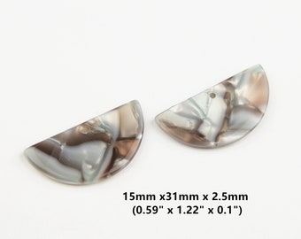 Könnte beinhalten: Zwei halbkreisförmige, weiße, braune und graue marmorierte Kunststoffperlen mit einem Loch in der Mitte. Die Perlen messen 15 mm x 31 mm x 2,5 mm (0,59" x 1,22" x 0,1").