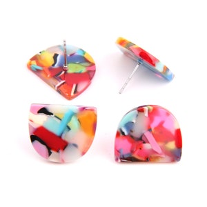 Puede incluir: Un par de pendientes coloridos en forma de semicírculo con un poste plateado. Los pendientes están hechos de un material translúcido con un patrón de remolino de rojo, rosa, azul, verde, amarillo y blanco.