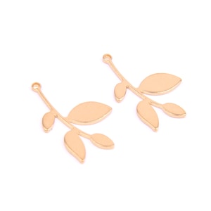 May include: Two gold-toned metal leaf branch charms with a loop at the top for attaching to jewelry or crafts.