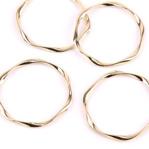 May include: Four gold-colored metal rings with a twisted design. The rings are all the same size and shape.