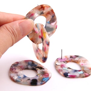 Puede incluir: Un par de pendientes de declaración de resina abstracta, multicolor y colorida. Los pendientes tienen forma de eslabón de cadena y tienen un cierre de poste.