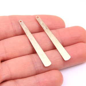 May include: Two gold-colored metal earring posts with a brushed finish.