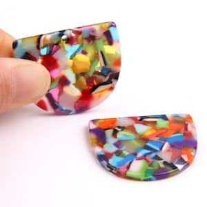 May include: Two colorful, half-circle shaped acrylic resin pendants with a mottled, confetti-like pattern. The pendants are translucent and feature a variety of colors, including red, orange, yellow, green, blue, purple, and white.