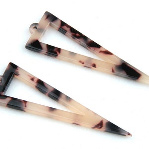 Puede incluir: Dos pendientes triangulares de color marrón y blanco con un patrón de mármol negro y blanco.