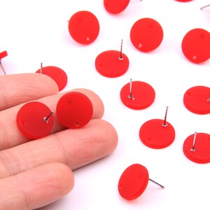 May include: A set of 15 red round earring studs with silver posts. The earrings are displayed on a white surface.