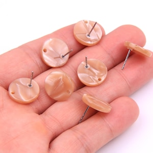 Puede incluir: Seis pares de pendientes redondos de resina marmoleada de color marrón claro con postes plateados.