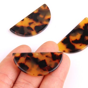 May include: Three brown and black tortoise shell half-circle shaped plastic pieces with a hole in the center.