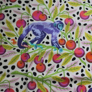 May include: Fabric with a repeating pattern of purple monkeys, red cherries, and green leaves on a cream background with black polka dots. The monkeys are perched on branches among the cherries.