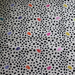 May include: White fabric with a black and white polka dot pattern and colorful ladybugs scattered throughout.