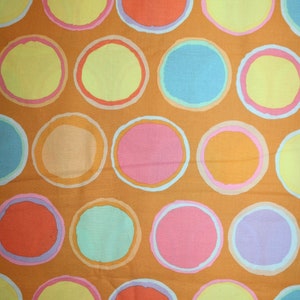 May include: Orange fabric with a repeating pattern of colorful circles. The circles are outlined in white and have a variety of colors, including yellow, pink, blue, and orange.