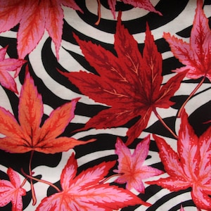 May include: A black and white zebra print fabric with a red, pink, and orange maple leaf pattern.