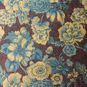 May include: A brown fabric with a floral pattern. The flowers are yellow and blue with a white center. The background is a dark brown with small white dots.