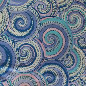 May include: Fabric with a repeating pattern of large, swirling spirals in shades of blue, teal, and pink. The design features detailed, textured lines within each spiral, creating a dynamic and visually appealing textile.