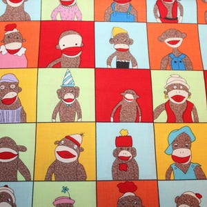 May include: A colorful fabric with a repeating pattern of monkeys wearing different hats and clothing. The monkeys are all smiling and have brown fur. The fabric is perfect for crafting projects, such as quilts, pillows, and bags.