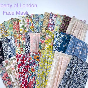 Puede incluir: Una colección de mascarillas de tela Liberty of London en varios patrones florales. Las mascarillas están hechas de algodón y tienen lazos para las orejas ajustables.