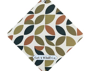 Peut inclure: Un désodorisant en forme de losange avec un motif géométrique de formes vert olive, bleu canard foncé et rouille sur fond blanc cassé. Le texte "Get A Whiff Co" est imprimé sur une petite étiquette en bas.