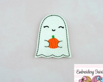 May include: A white ghost-shaped patch with a smiling face and holding an orange pumpkin. The patch has a black stitched outline and is likely for Halloween or fall-themed crafts. The patch is a cute, whimsical design.