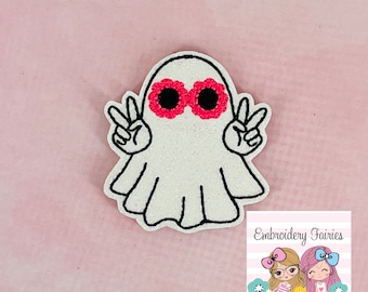 May include: White ghost with pink flower-shaped sunglasses and peace signs, embroidered on a white background.