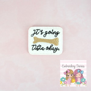 May include: White felt patch with black embroidery that reads "It's going tibia okay." with a gold embroidered bone in the middle.