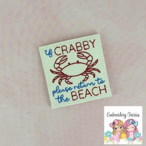 Puede incluir: Parche bordado cuadrado con el texto "If Crabby please return to the BEACH" y una ilustración de cangrejo rojo. El parche tiene un fondo blanco y costuras azules.