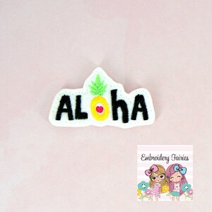 May include: White felt patch with black embroidered text "Aloha" and a yellow pineapple with a red heart in the centre.