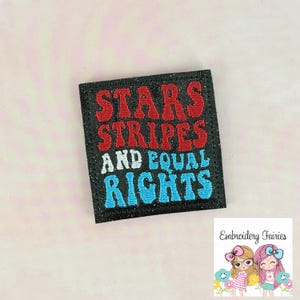May include: A black square patch with the words "STARS STRIPES AND EQUAL RIGHTS" embroidered in red, white, and blue. The patch has a glittery texture and a stitched border. The image also includes a logo of two cartoon fairies.