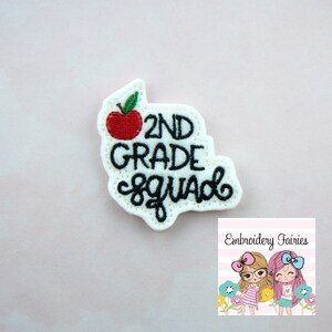 Puede incluir: Parche de fieltro blanco con bordado negro que dice "2nd Grade Squad" con un gráfico de manzana roja.