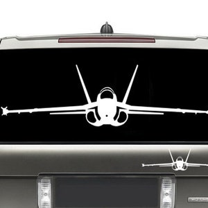 May include: A white silhouette of a fighter jet is displayed on the rear window of a silver SUV. The jet is facing forward with its wings spread out. A smaller silhouette of the same jet is displayed below the larger one.