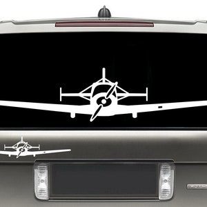 May include: A white silhouette of a small airplane with a propeller on a black background. The airplane is on the back window of a silver SUV.