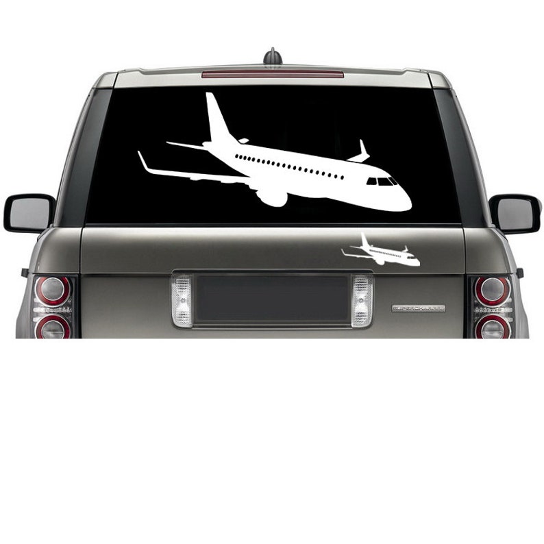 May include: A white silhouette of a plane is on the back window of a silver SUV. The plane is facing to the right and has a smaller plane silhouette below it.