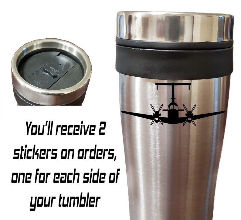 以下が含まれることがあります： 黒い蓋と中央に黒いバンドが付いたステンレス製のトラベルマグ。マグには、前面に小さな飛行機の黒いシルエットが描かれています。「You'll receive 2 stickers on orders, one for each side of your tumbler」という黒いテキストが画像の下に書かれています。