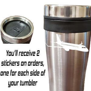 May include: Stainless steel travel mug with a white airplane silhouette design. The mug has a black lid and a black band around the middle. "You'll receive 2 stickers on orders, one for each side of your tumbler" is written in black text on a white background.