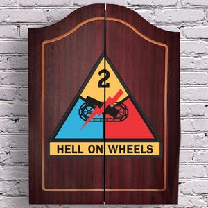 May include: A dark wood cabinet with two doors featuring a centered triangular emblem of the 2nd Armored Division. The emblem displays a yellow top section with the number 2, a blue left section, a red right section, a black tank track, a red lightning bolt, and the text HELL ON WHEELS.